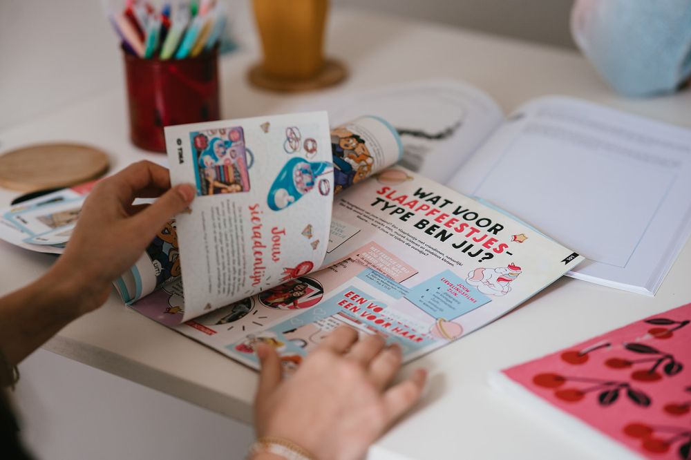 Meisje knipt plaatjes uit tijdschrift om een collage te maken in het werkboek Werken aan je Zelfbeeld.
